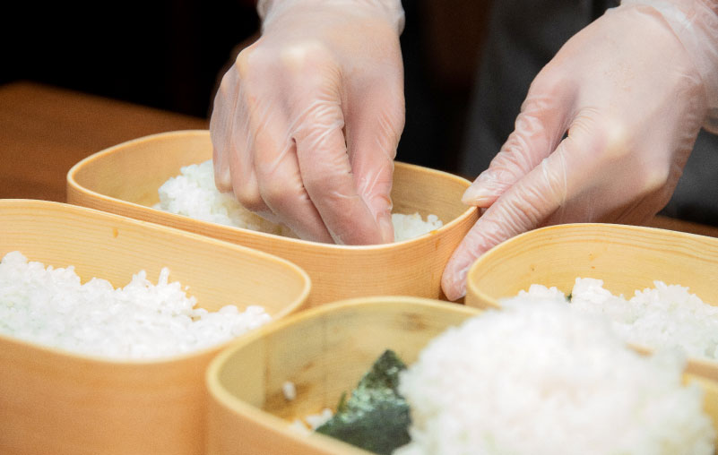 経木の弁当箱にご飯を詰めるところ