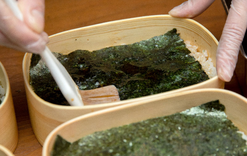 弁当箱に敷いた海苔に自家製の鰹出汁醤油を塗るところ